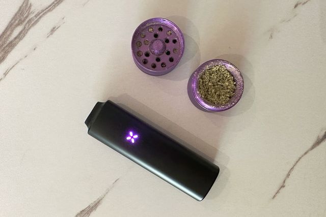 a pax plus showing a purple light sitting next to a purple grinder with green weed in it