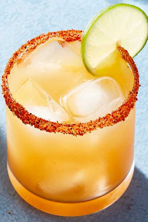 peach margarita with a spicy rim garnished with a lime wheel
