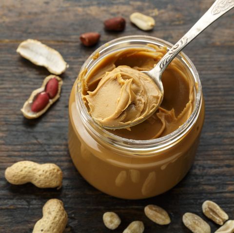 peanut paste in an open jar and peanuts