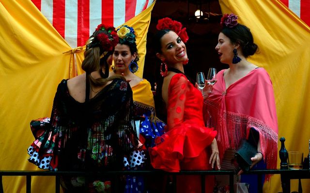 a woman wearing a traditional sevillian dress smiles as she drinks fino wine with friends during the feria de abril april fair in sevilla on april 30, 2017   the fair dates back to 1847 when it was originally organized as a livestock fair but has turned into a week of flamenco dancing, music and bullfighting photo by cristina quicler  afp        photo credit should read cristina quiclerafp via getty images