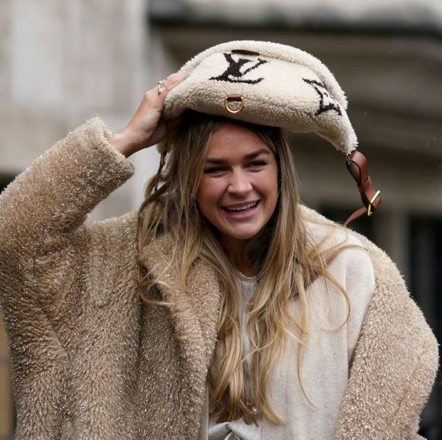 london, england   february 16 a guest wears a brown fluffy coat, and uses a vuitton fanny pack bag to cover from the rain, during london fashion week fall winter 2020 on february 16, 2020 in london, england photo by edward berthelotgetty images