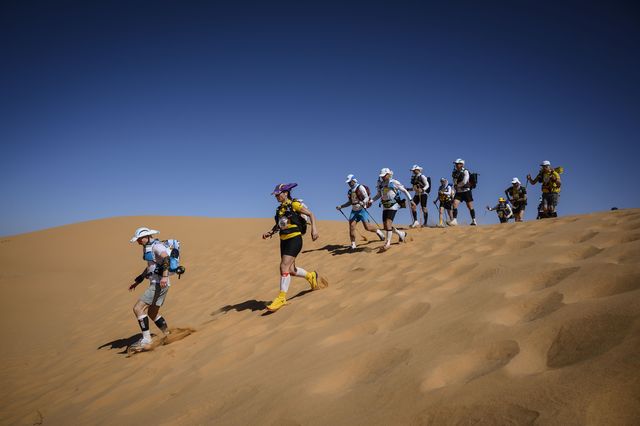 varios corredores bajan una duna del desierto durante el maratón des sables de marruecos