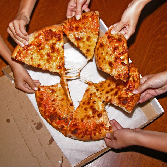 People grabbing slices of pizza, overhead view