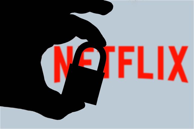 imagen de una mano a contraluz sujetando un candado con una pantalla con el logo de netflix al fondo