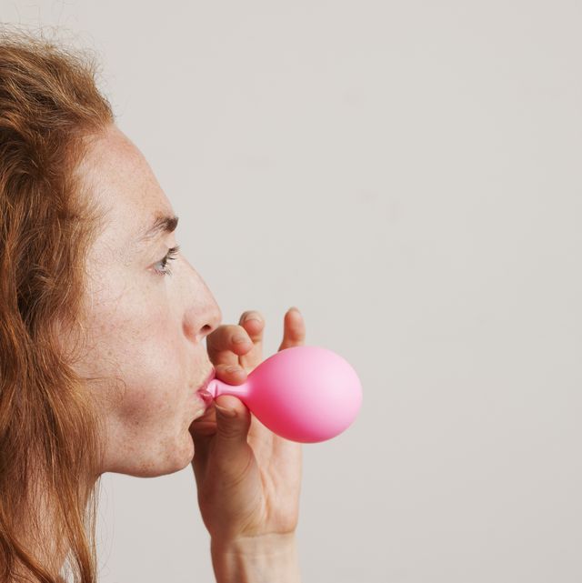 period bloating a model released profile of young woman with red hair blowing up pink balloon