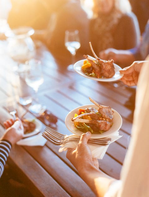 one person carrying two meals to a table at a summer party bbq in the garden