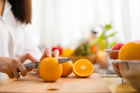 person cutting to make juice from fresh oranges on wooden table