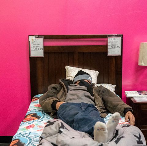 a man in a beanie takes a nap on a wooden bed at gallery furniture store in houston, which transformed into a warming station and opened its doors to cold texans who lost power