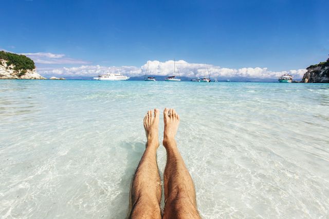 personal perspective of man's feet in clear turquoise water
