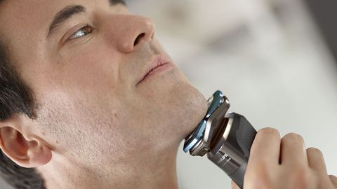 un hombre de mediana edad se afeita con la maquina wet dry de philips serie 7000