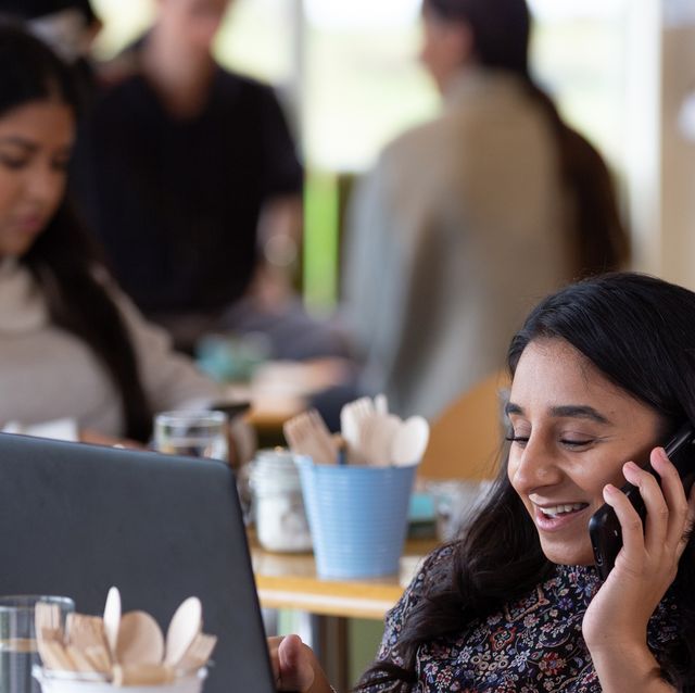 lächelnde frau, die auf smartphone im café generische technologie spricht