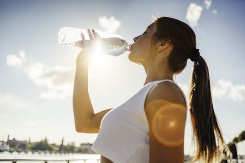 Mujer bebiendo agua mientras corre.