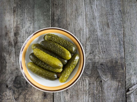 Pickled green gherkins in a bowl on a wooden table