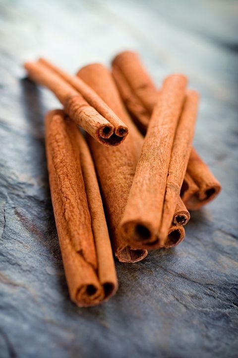 pile of cinnamon sticks on a dark textured surface