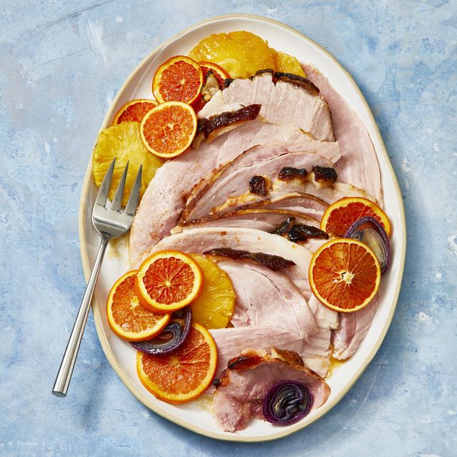 pineapple glazed ham with slices of citrus on a white plate