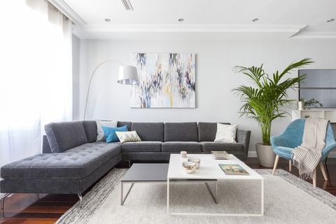 salón moderno con sofá con chaise longue gris y mesas nido