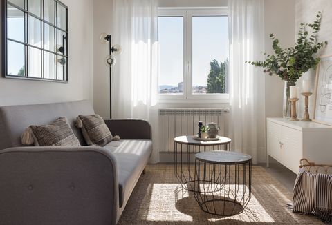 salón nórdico con sofá gris, espejo con cuarterones y mesas a dos alturas