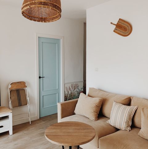 salón mediterráneo con sofá beige, mesa de centro de madera redonda y lámpara de fibras