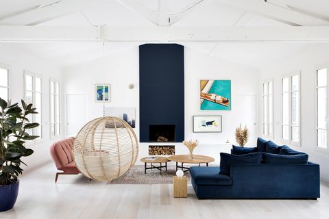 salón de diseño moderno con chimenea, sofá de terciopelo azul y columpio de ratán
