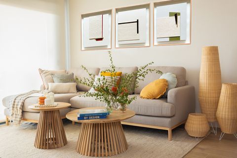 salón con sofá con chaiselongue gris, mesas de centro de madera redondas y lámparas de fibras
