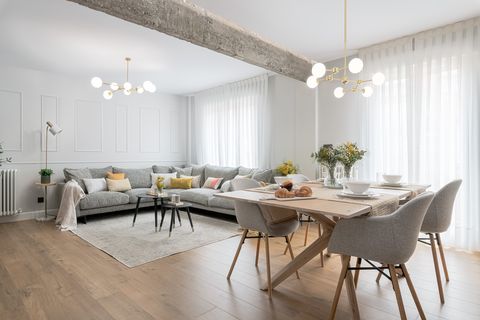 salón comedor de diseño moderno con viga de hormigón visto y sofá esquinero gris