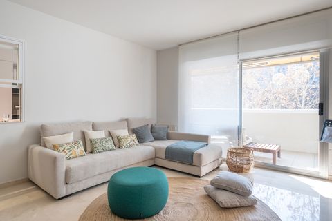 salón con sofá con chaise longue gris, alfombra de fibras redonda y puf azul
