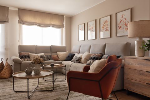 salón con sofá rinconera beige, mesas de centro redondas y butaca de terciopelo terracota