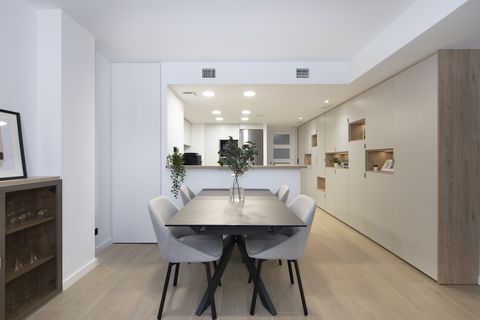 cocina abierta con barra y muebles a medida y comedor moderno con mesa negra y sillas grises