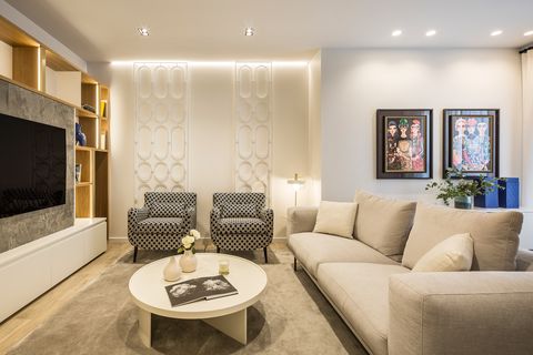 salón de diseño moderno con sofá beige, butacas con motivos geométricos y mesa de centro blanca