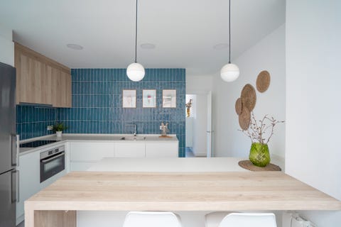 cocina con azulejos azules y barra de desayunos de madera