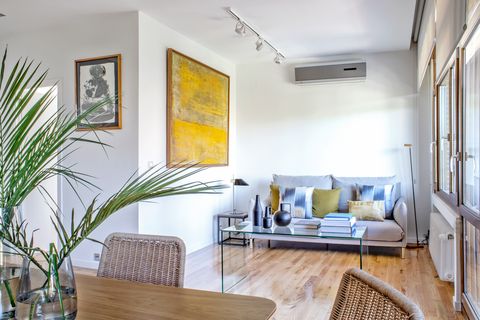 salón comedor con sofá gris y cuadro abstracto en color mostaza