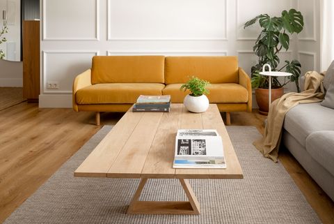 salón con molduras en la pared, sofá de terciopelo mostaza, sofá gris y mesa de centro de madera