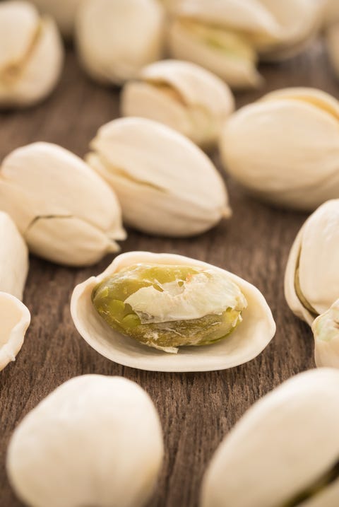 Best Fat Burning Foods - Shelled Pistachios a shelled pistachio and pistachios in shells on a wooden table, a good housekeeping pick for a healthy weight loss food