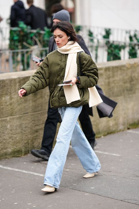 paris, france january 22 a guest wears a white latte wool scarf, a khaki puffer jacket, blue faded denim flared pants, white latte shiny leather pointed block heels ankle shoes , outside wooyoungmi, during paris fashion week menswear fall winter 2023 2024, on january 22, 2023 in paris, france photo by edward berthelotgetty images