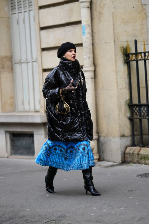 paris, france january 23 a guest wears a black wool beret hat, green and blue rhinestones flower pattern, a black shiny varnished leather high neck long puffer jacket, a blue with black embroidered sequined pearls pattern long dress, black shiny leather pointed heels knees boots high boots, black tulle with embroidered rhinestones mittens, a black nylon with gold embroidered pattern circle handbag, during paris fashion week haute couture spring summer, on january 23, 2023 in paris, france photo by edward berthelotgetty images