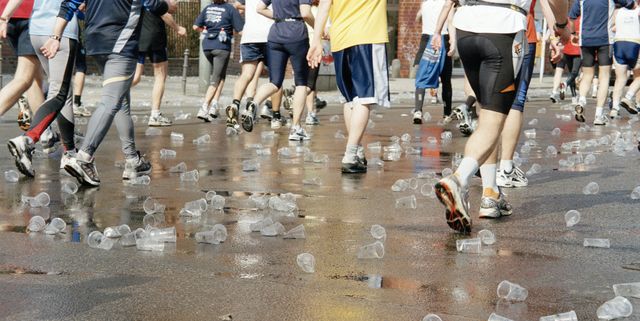 plastic cups scattered over road beneath marathon runners
