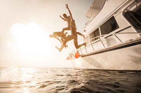 playful people jumping from the boat into the sea