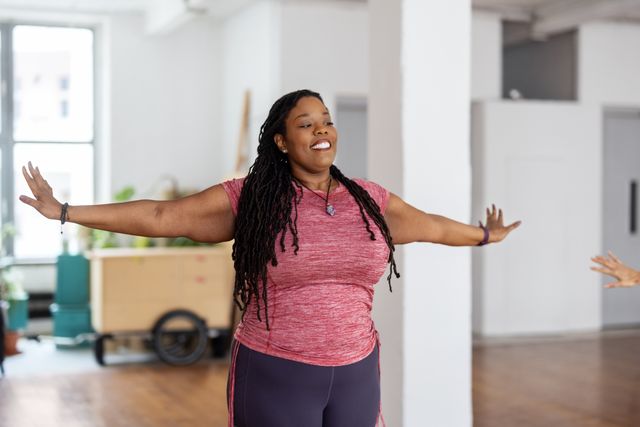 plus size african woman doing stretching workout in yoga studio