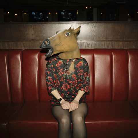 Portrait female millennial wearing horse head in nightclub
