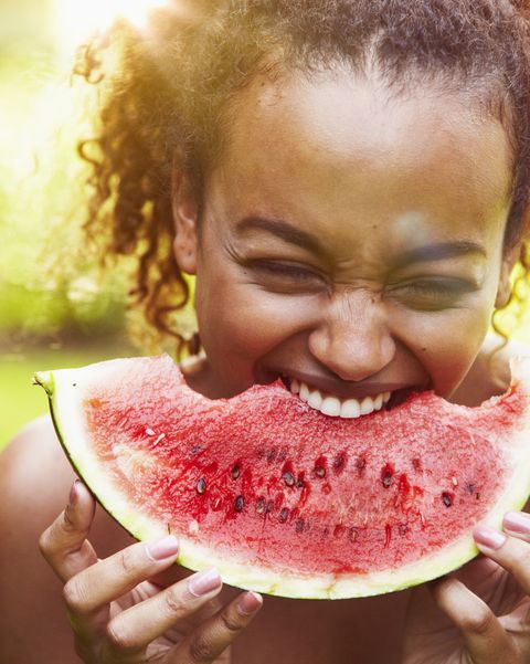 portrait of a young woman eating watermelon on a sunny day, backlit