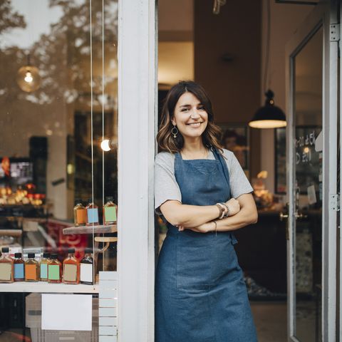 portrait of confident female owner standing at entrance of deli