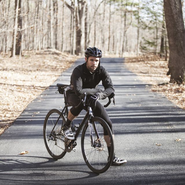 portrait of cyclist with bicycle standing on road at forest