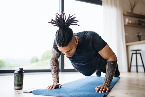 a portrait of fit mixed race man with dreadlocks doing exercise at home