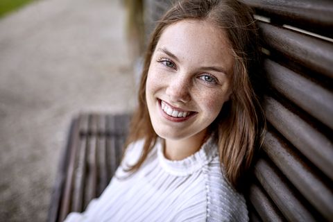 Portrait of happy young woman sitting on a bench