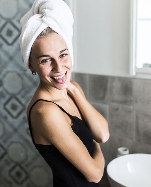 Portrait of happy young woman with hair wrapped in a towel in bathroom