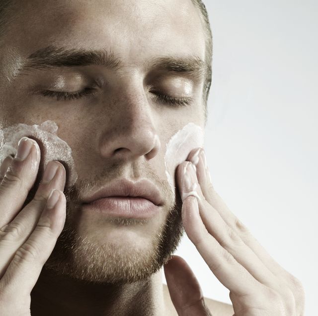 portrait of man applying moisturizer to face