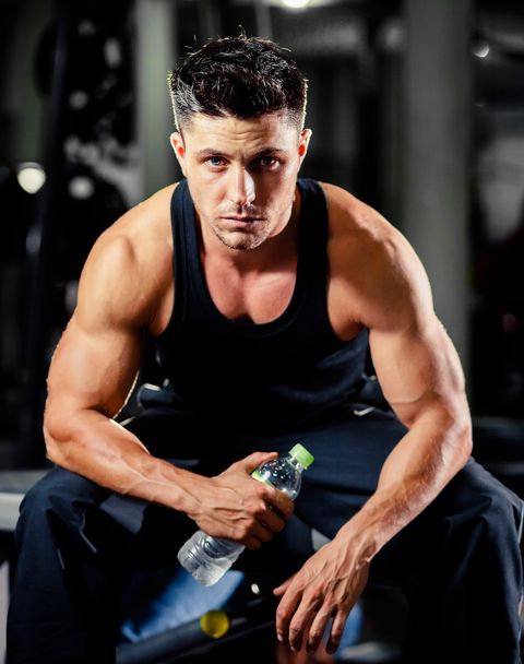 Portrait Of Muscular Man Sitting At Gym