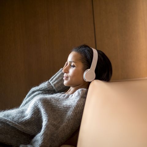 portrait of relaxed young woman listening music with headphones on couch