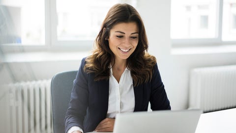 portrait of smiling businesswoman sitting at desk in the office working on laptop