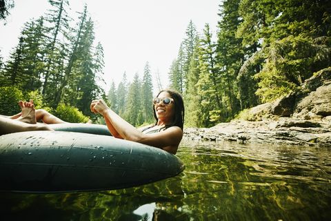 Portrait of smiling woman floating down river in inner tube on summer afternoon